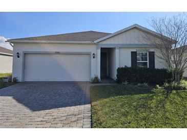 Charming single-story home featuring a well-manicured lawn, a two-car garage, and inviting curb appeal at 1046 Wanderer Dr, Deltona, FL 32738