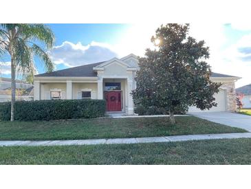 Charming home featuring a red door, well-maintained lawn, trimmed hedges, and mature landscaping at 1966 Derby Glen Dr, Orlando, FL 32837