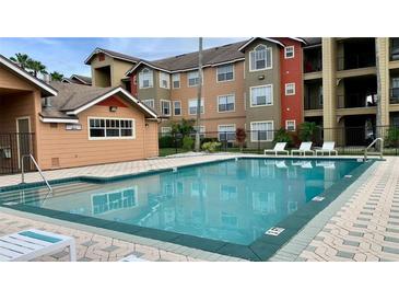 Exterior view of a community pool with poolside seating and nearby apartment buildings in the background at 2212 Grand Cayman Ct # 1616, Kissimmee, FL 34741