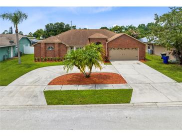 Charming brick home featuring a well manicured lawn, circular driveway, and mature landscaping at 2408 Sweetwater Blvd, St Cloud, FL 34772