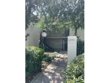 Inviting condo exterior with lush landscaping, stone walkway, and stairs to the upper level at 3240 S Semoran Blvd # 14, Orlando, FL 32822
