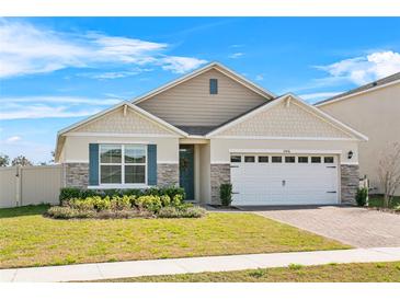 Charming single-Gathering home featuring a brick driveway, lush landscaping, and a two-car garage at 33436 Country House Dr, Sorrento, FL 32776