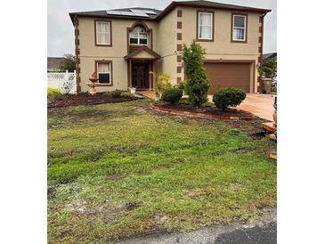 Two-story stucco home featuring a well-maintained front yard and a two-car garage at 350 Corsica Ct, Kissimmee, FL 34758