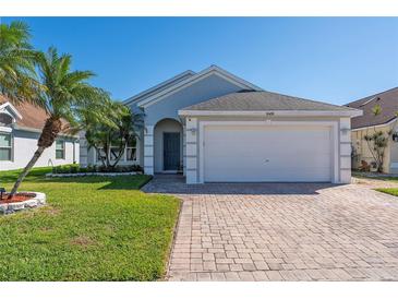 Charming single Gathering home featuring a two car garage, paver driveway, and lush tropical landscaping at 6410 Cherry Grove Cir, Orlando, FL 32809