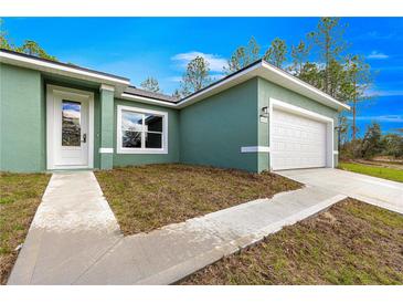 Lovely, bright home featuring a one car garage, and manicured lawn under a beautiful blue sky at 6430 Sw 144Th Street Rd, Ocala, FL 34473