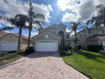 Charming two-story home with lush landscaping, a brick driveway, and a two-car garage at 723 Tuscan Hills Blvd, Davenport, FL 33897