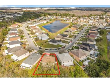 Aerial view of a home in a suburban neighborhood with a pond and tree-lined streets at 10409 Laxton St, Orlando, FL 32824