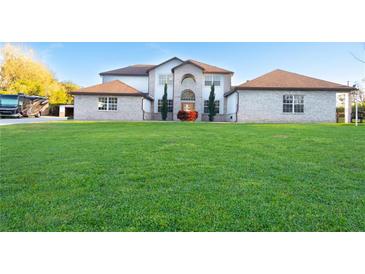 Expansive, well-manicured lawn with a beautiful two-story home showcasing a light brick facade at 15350 Arabian Way, Montverde, FL 34756