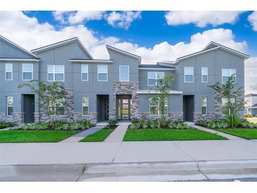 Modern townhome featuring a contemporary design with stone accents and well-maintained landscaping at 1696 Tropical Palms Cir, Kissimmee, FL 34747