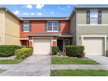 Charming townhouse featuring a one car garage, black shutters, manicured landscaping, and a cozy front entrance at 565 Cresting Oak Cir # 87, Orlando, FL 32824