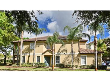 Charming tan two-story townhome with a red tile roof, palm trees, and a well-manicured lawn at 8766 The Esplanade # 23, Orlando, FL 32836