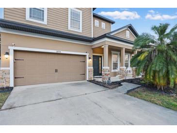 A tan two-story home featuring a garage and front porch with brick pillars, offering curb appeal at 1894 Valley Forge Dr, St Cloud, FL 34769