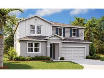 Charming two-story home featuring a two-car garage, landscaped yard, and a mix of siding and stucco facade at 1111 Olivine Ave, Dundee, FL 33838