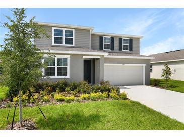 Charming two-story home featuring a two-car garage, beautiful landscaping, and a welcoming front entrance at 1127 Olivine Ave, Dundee, FL 33838