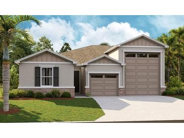 Charming one-story home featuring a two-car garage, stone accents, and lush landscaping at 1139 Olivine Ave, Dundee, FL 33838