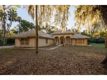 Beautiful, single-story home featuring a unique roof design and lush, mature landscaping at 1695 Horseshoe Rd, Enterprise, FL 32725