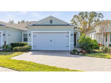 Charming home featuring a two-car garage with brick paved driveway and mature landscaping at 1873 Flora Pass Pl, Kissimmee, FL 34747