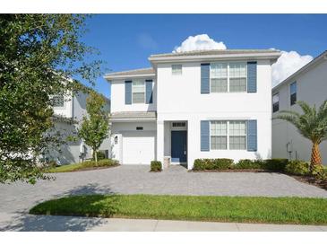 Charming two-story home showcasing blue shutters, a gray driveway, and well-maintained landscaping at 4768 Kings Castle Cir, Kissimmee, FL 34746