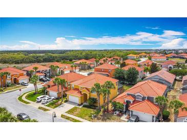 Expansive aerial view of a residential neighborhood with orange tile roofs and lush landscaping on a sunny day at 131 Stella Pass, Davenport, FL 33837