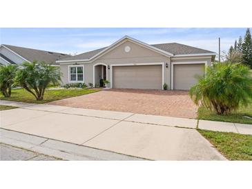 Charming home with a two-car garage and a brick-paved driveway complemented by lush landscaping at 2711 Wadeview Loop, St Cloud, FL 34769