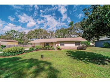 Charming single-story home featuring a lush green lawn and neatly landscaped garden beds beneath a cloudy blue sky at 6449 Eve St, St Cloud, FL 34771