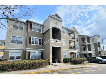 Modern condominium exterior with tan siding, red shutters, and well-maintained landscaping under a blue sky at 8137 Claire Ann Dr # 203, Orlando, FL 32825