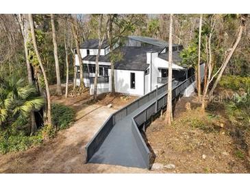 An inviting two-story home with a walkway surrounded by lush trees at 104 Wild Plum Ln, Longwood, FL 32779