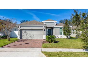 Charming single-Gathering home featuring a well-maintained lawn, brick driveway, and two-car garage at 1097 Hendon Loop, Davenport, FL 33837