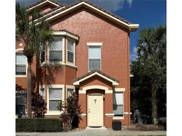 Charming two-story townhome with a welcoming front entrance and lush tropical landscaping at 19934 Villa Isle # 107, Orlando, FL 32821