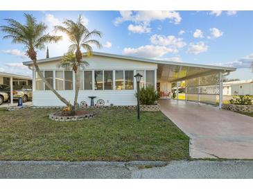 Charming home featuring a front yard with palms, a carport and an enclosed front porch at 6719 Canterbury Ne Dr, Winter Haven, FL 33881
