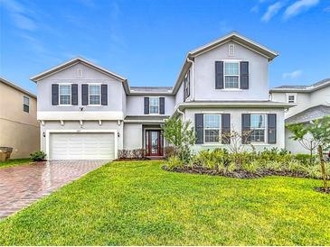 Inviting two-story home with a well-manicured lawn and brick-paved driveway at 7641 Modica St, Clermont, FL 34714
