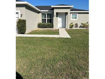 Well-maintained front yard featuring a green lawn, walkway leading to the front door, and manicured bushes at 1664 Redfin Dr, Kissimmee, FL 34759