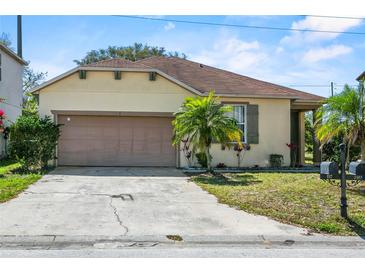 Charming single-Gathering home with a tan exterior, attached garage and a well-manicured front yard at 217 Sand Ridge Dr, Davenport, FL 33896