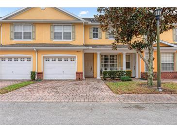 Charming townhome featuring a brick driveway, two-car garage, and inviting front porch with white columns at 4925 Poolside, St Cloud, FL 34769