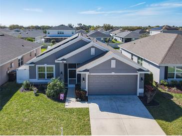 Front exterior view of a well-manicured home with a gray exterior and two-car garage at 649 Meadow Pointe Dr, Haines City, FL 33844