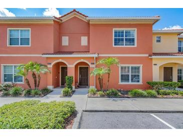 Charming townhouse featuring a terracotta-colored facade, arched doorways, and lush landscaping at 8974 California Palm Rd, Kissimmee, FL 34747