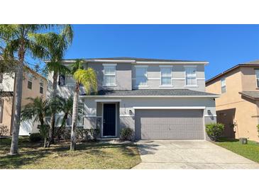 Charming two-story home featuring a two-car garage and lush tropical landscaping at 1113 Pine Ridge Dr, Davenport, FL 33896