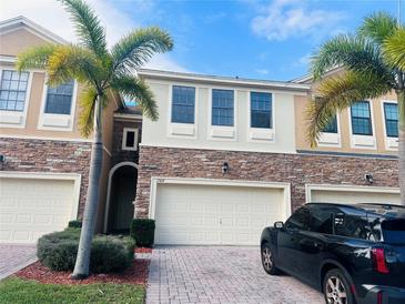 Inviting townhome featuring brick accents, attached garage, manicured lawn, and tropical palm trees at 1509 Portofino Meadows Blvd, Orlando, FL 32824