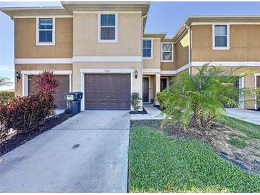 Inviting townhome featuring a well-kept lawn, landscaping, and an attached single-car garage at 1510 Chelsea Dr, Davenport, FL 33897