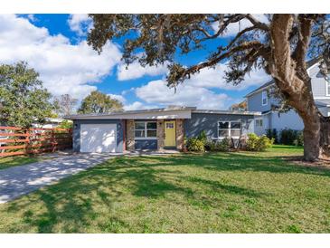Charming single-story home with a well-maintained lawn, a light-grey exterior, and a driveway leading to an attached garage at 4217 Park Lake St, Orlando, FL 32803