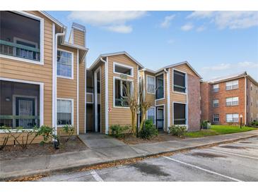 Two-story condo with tan siding, well-maintained landscaping and visible parking area at 5530 Chrishire Way # D204, Orlando, FL 32822
