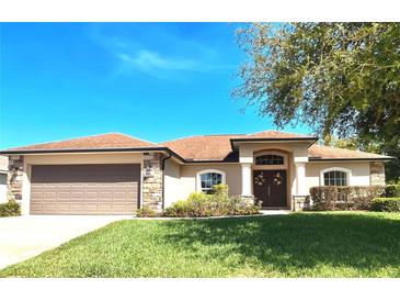 Charming single-story home featuring a well-manicured lawn, stone accents, and a welcoming double-door entryway at 151 Lake Arietta Ct, Auburndale, FL 33823