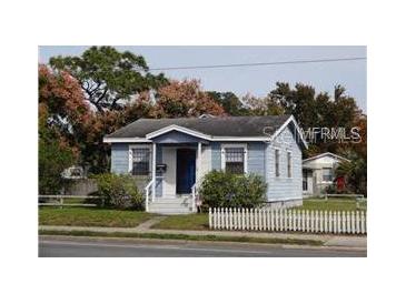 Charming single-story home featuring a blue exterior, complemented by a neatly kept yard and white picket fence at 4707 Edgewater Dr, Orlando, FL 32804