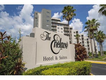 Hotel & Suites sign with lush landscaping and palm trees in front of the building on a sunny day at 6165 Carrier Dr # 2108, Orlando, FL 32819