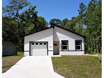 Modern, newly constructed single-story home with a bright white exterior, dark trim and an attached garage at 6862 Se 23Rd Ave, Ocala, FL 34480