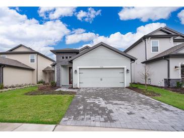 Charming single-Gathering home features a two-car garage, stone accents, and manicured front lawn at 7848 Somersworth Dr, Kissimmee, FL 34747