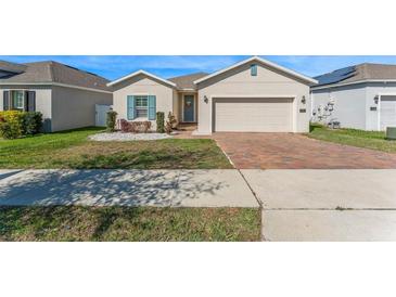 Charming single-story home features a brick driveway, blue shutters, and a well-maintained front yard at 485 Disa Dr, Davenport, FL 33837