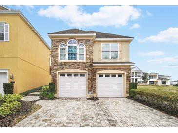 Charming two-story home featuring a stone facade and two-car garage and well manicured yard at 7623 Excitement Dr, Reunion, FL 34747