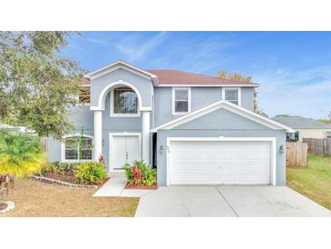 Charming two-story home with a two car garage, manicured landscaping, and a light blue exterior at 943 Van Loon Ct, Kissimmee, FL 34758