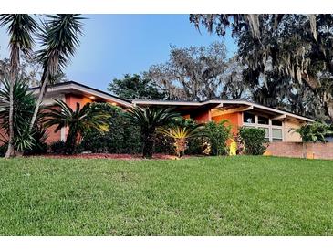 Charming single-story home with lush landscaping and mature palm trees under a twilight sky at 5019 Saint Germain Ave, Orlando, FL 32812